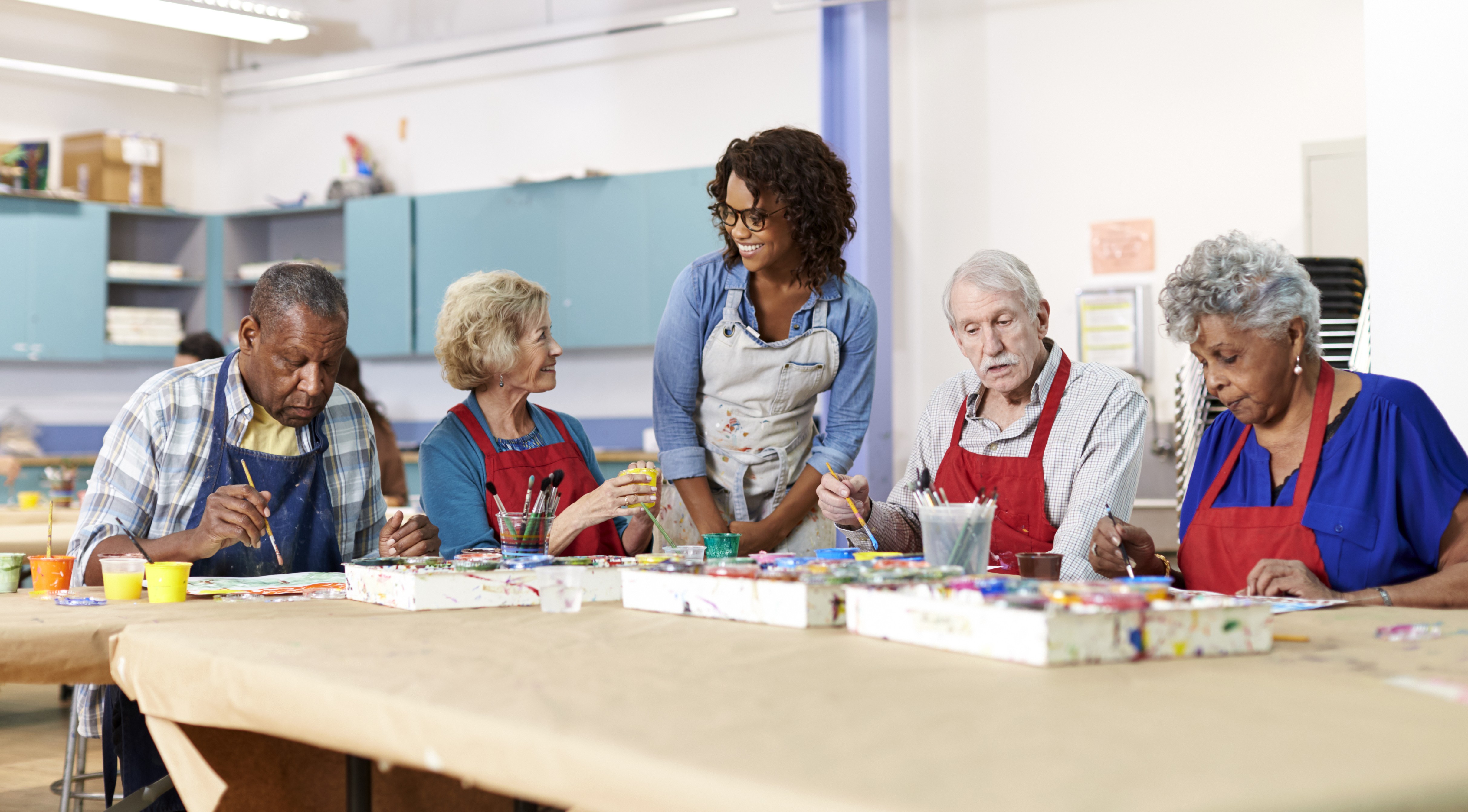 A group of elderly individuals participating in an art class at a day care center in Philadelphia, guided by a caregiver. Engaging activities promote social interaction and well-being.